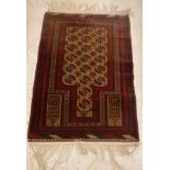 A Bokhara prayer rug with repeating elephant foot medallion decoration on a fawn ground within a