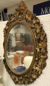 A Victorian carved giltwood and gesso framed oval wall mirror with grape and vine decoration in the