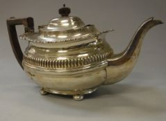 An Edwardian silver teapot with reeded banded decoration and gadrooned and shell decorated rim on