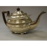 An Edwardian silver teapot with reeded banded decoration and gadrooned and shell decorated rim on