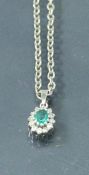 A white gold emerald and diamond set pendant