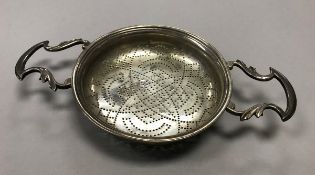 A George II silver twin-handled lemon strainer (possibly by Benjamin Cartwright I, London 1748),