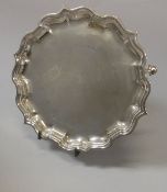 A George VI silver card tray in the 18th Century manner with piecrust rim raised on three hoof feet