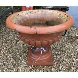 A large terracotta urn of typical form raised on a square base