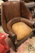 A wing back armchair with brown studded leather and carved front rail