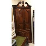 A George II walnut free-standing corner cupboard with swan neck pediment and a carved centre finial