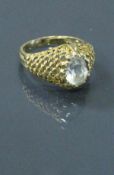 A 9 carat gold ring with aquamarine set stone centre, the shoulders of stylised net design,