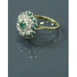 An 18 carat gold emerald and diamond daisy cluster ring 4.