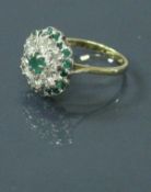 An 18 carat gold emerald and diamond daisy cluster ring 4.