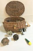 A wicker fishing basket containing reels by Intrepid, Allcocks, Harrington,