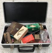 A case containing various shooting requisites including cleaning brushes, loading machine,