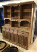 A modern pine dresser with multi shelved plate rack over three drawers and three pairs of cupboard