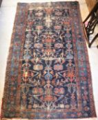 A Persian rug, the central panel set with stylised floral decoration on a dark blue ground,