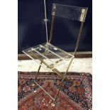 A set of four modern clear perspex and brassed framed folding chairs