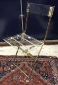 A set of four modern clear perspex and brassed framed folding chairs