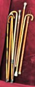 A collection of six various modern walking sticks/canes and a hanging cane with ten angle cut slits,