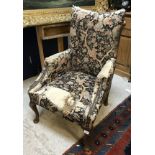 An upholstered swept armchair in the Georgian style raised on cabriole legs to pad feet