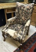 An upholstered swept armchair in the Georgian style raised on cabriole legs to pad feet