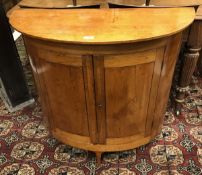 A 19th Century Scandinavian pine cupboard of demilune form the plain top over two doors on simple