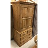 A modern pine wardrobe with two cupboard doors over two short and two long drawers