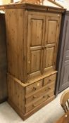 A modern pine wardrobe with two cupboard doors over two short and two long drawers