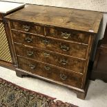 An early 18th Century walnut chest the quartered top feather banded over two short and three long