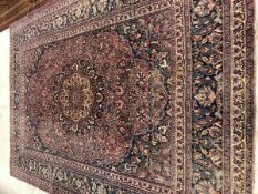A Persian rug, the central medallion on a plum ground, within a foliate decorated border,
