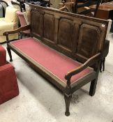 A 19th Century oak settle with four fielded panel back over an upholstered seat on cabriole legs to