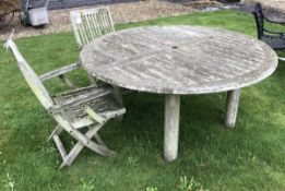 A modern teak slatted circular garden table on turned legs and two slatted elbow chairs