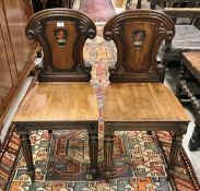 A pair of early 19th Century mahogany panel seated hall chairs with amorial decorated back as a