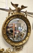 A circular gilt-framed convex mirror in the Regency manner with eagle surmount