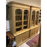 A pair of modern oak bookcase cabinets with glazed two door upper sections over panelled two door