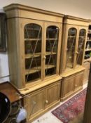 A pair of modern oak bookcase cabinets with glazed two door upper sections over panelled two door