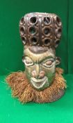 A 20th Century West African carved hardwood and brass and copper embellished helmet mask with grass