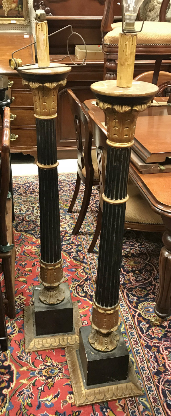 A pair of ebonised and gilt standard lamps in a classical corinthian style with curved leaf