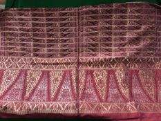 An early 20th Century Indian deep red silk table cover decorated in gold and silver wire with