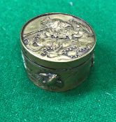 An early 20th Century Chinese brass cylindrical lidded box decorated in relief to the lid with