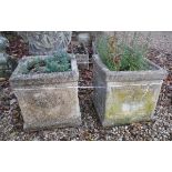 A pair of reconstituted stone planters with urn decoration to the side panels