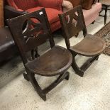 Two similar tribal carved hardwood chairs with pierced backs and demi-lune adzed seats,