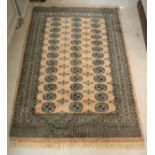 A modern Bokhara rug with repeating elephant foot medallions on a pale pink ground within a stepped