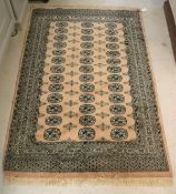 A modern Bokhara rug with repeating elephant foot medallions on a pale pink ground within a stepped