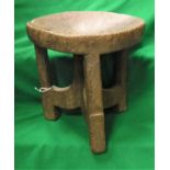 A west African carved wooden stool with circular dished seat on three supports united by centre