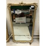 A gilt framed mirror with carved scroll decoration