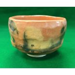 A modern Japanese raku yaki akaraku chawan with orange glaze, bears impressed mark to base,