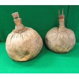 Two tribal gourd shaped water carriers with wooden stoppers, one decorated with a pair of horns,