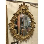 A giltwood and gesso framed wall mirror decorated with floral sprays in the Rococo manner