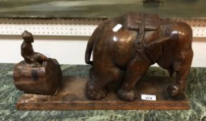 An Indian hardwood sculpture of an elephant with figure on log behind