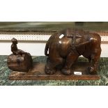 An Indian hardwood sculpture of an elephant with figure on log behind