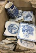 A box containing assorted blue and white Delft ware and other tiles set with various topographical