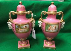A pair of 19th Century pink ground porcelain lidded urns in the Vienna manner decorated with panels